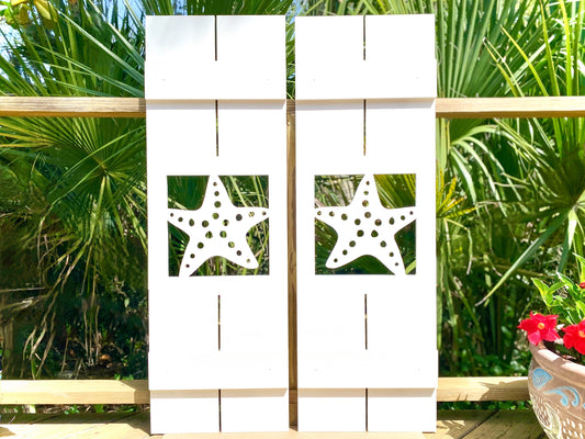 Exterior board and batten style coastal window shutters with starfish seastar cutout. Weatherproof PVC beach house shutters for outdoor decor.
