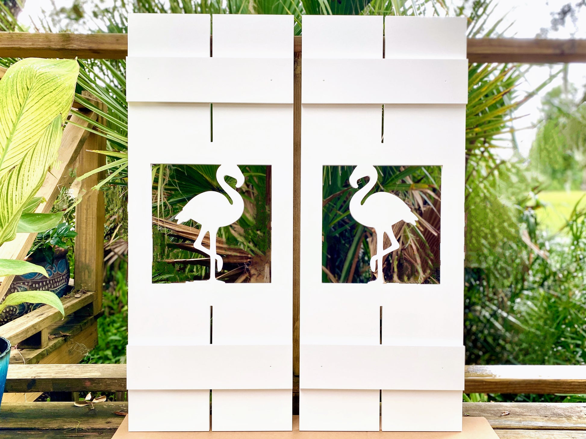 Exterior board and batten style coastal window shutters with tropical flamingo bird cutout. Weatherproof PVC beach house shutters for outdoor decor.