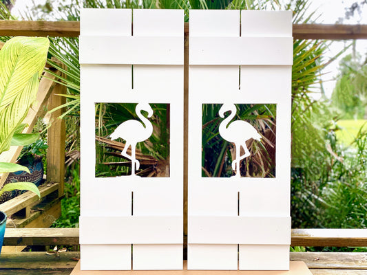 Exterior board and batten style coastal window shutters with tropical flamingo bird cutout. Weatherproof PVC beach house shutters for outdoor decor.