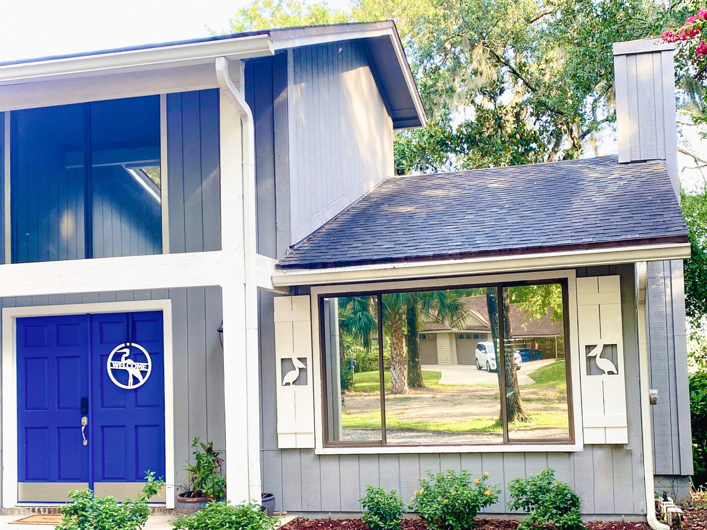 Exterior board and batten style coastal window shutters with pelican bird cutout. Weatherproof PVC beach house shutters for outdoor decor.